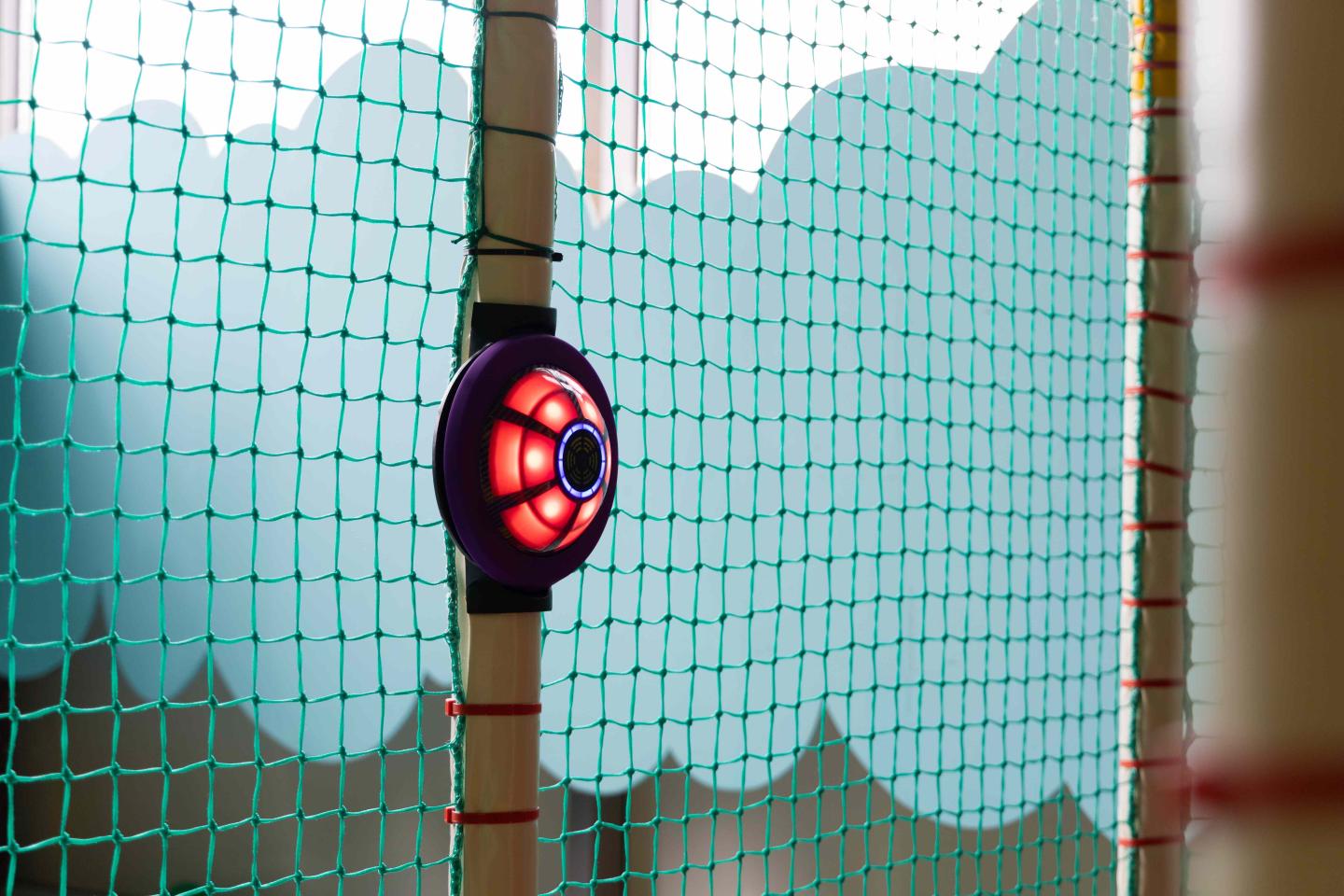 Actieve JB-TAG sensor met rood licht gemonteerd aan een paal in een indoor speelstructuur met veiligheidsnetten, klaar voor interactief spel.