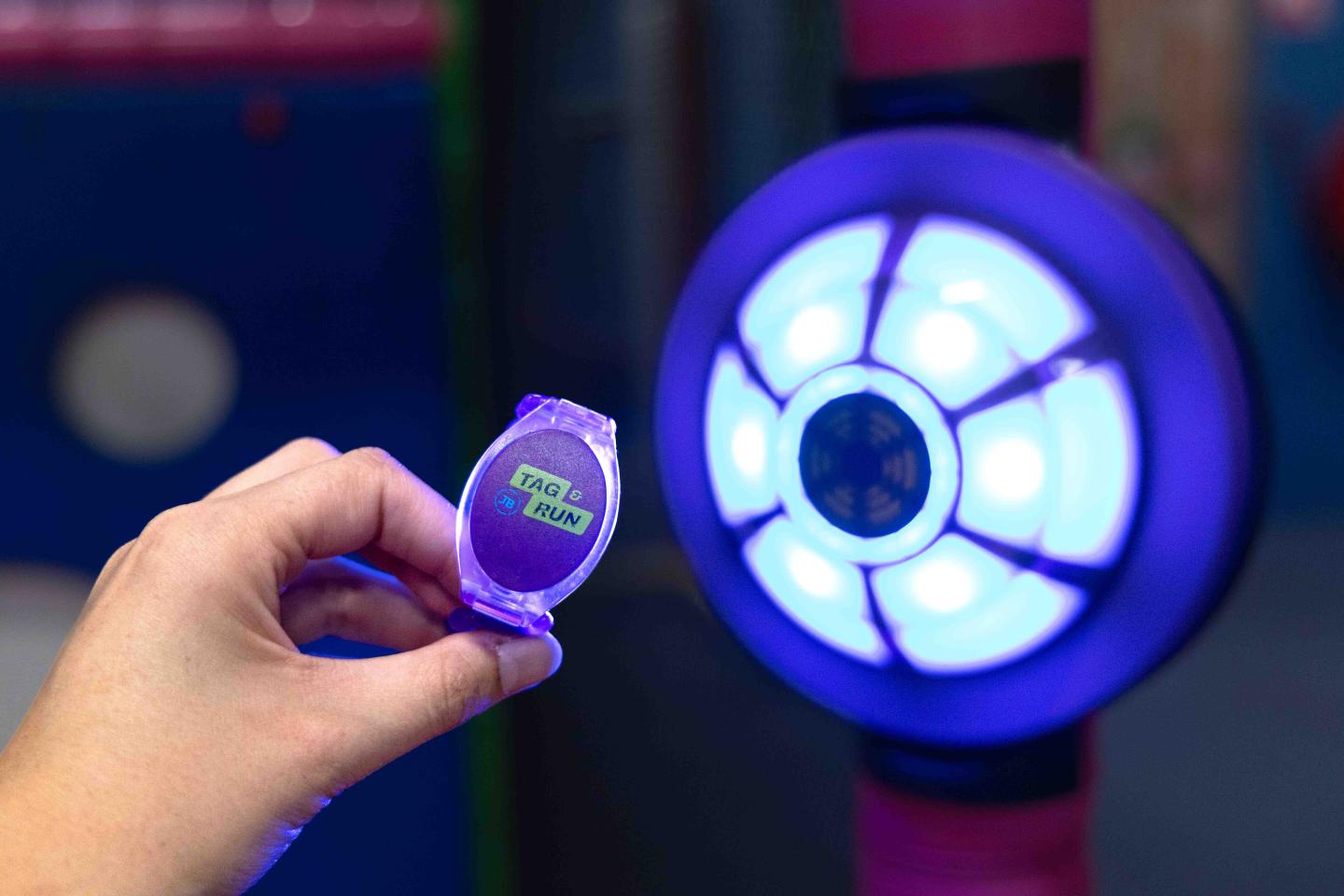 Hand met een JB-TAG speelbandje voor een oplichtend interactief doel in een indoor speellocatie