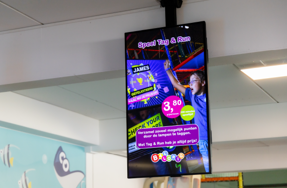 Digitale reclamezuil in een speelhal met promotie voor het interactieve spel Tag & Run bij Ballorig.