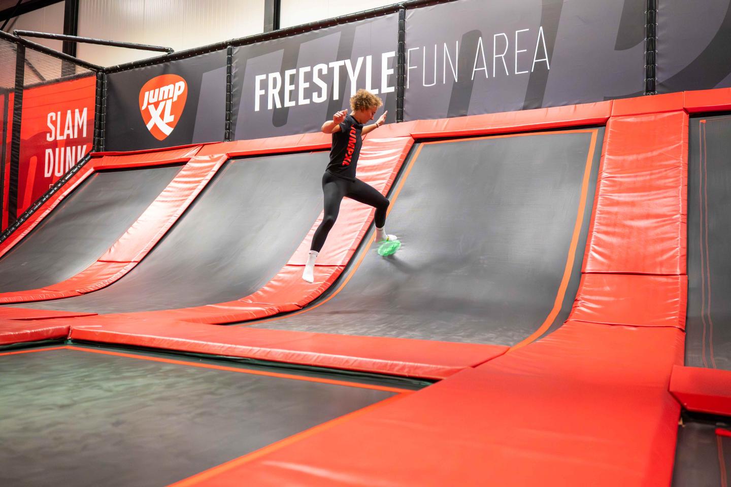 Speler met voetbandje raakt een lichtgevende spot tijdens Tag & Jump trampoline spel.