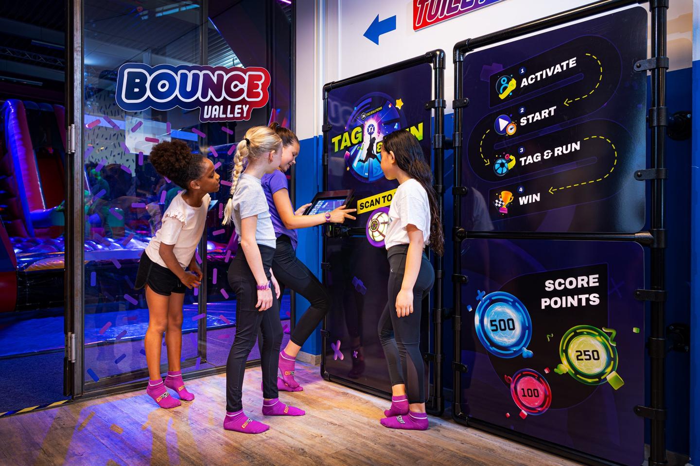 ier kinderen starten een spel bij het JB Tag & Run systeem in een indoor speeltuin