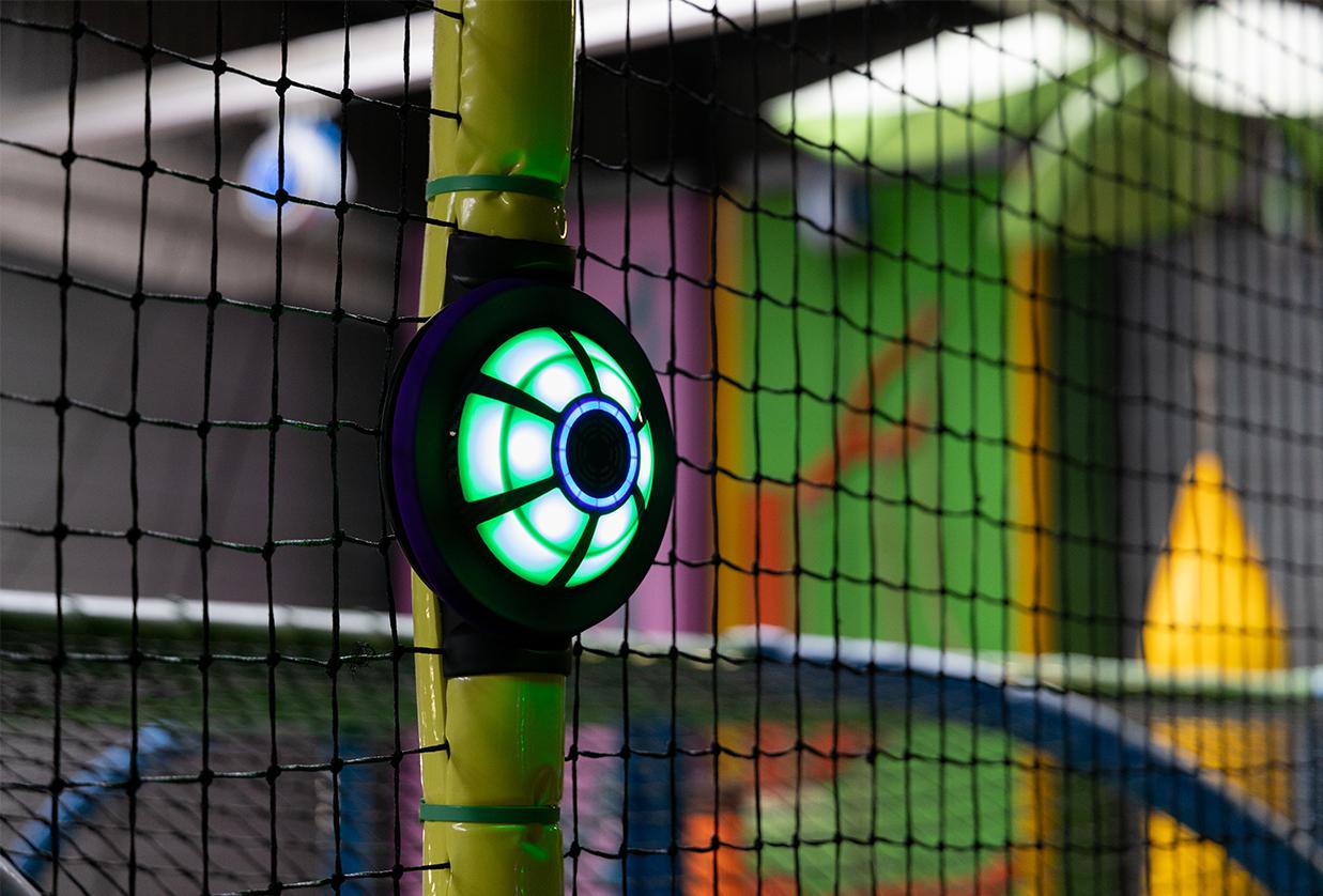 Close-up van een geactiveerde interactieve tag-lamp van het JB-TAG systeem van JB Tag Solutions, bevestigd aan een speelstructuur in een indoor speelhal