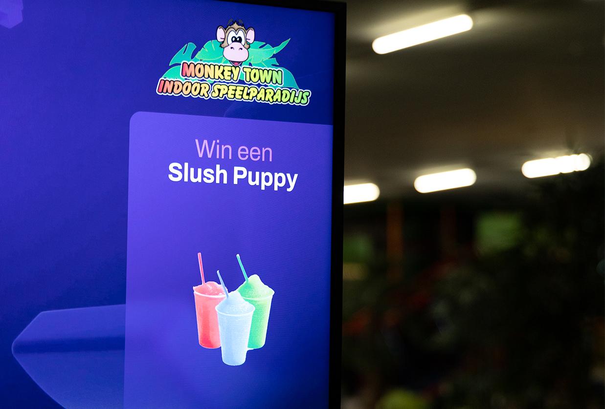 Interactief scherm van JB Tag Solutions bij een indoor speelparadijs, dat spelers via het JB-TAG systeem beloont met een Slush Puppy bij een hoge score